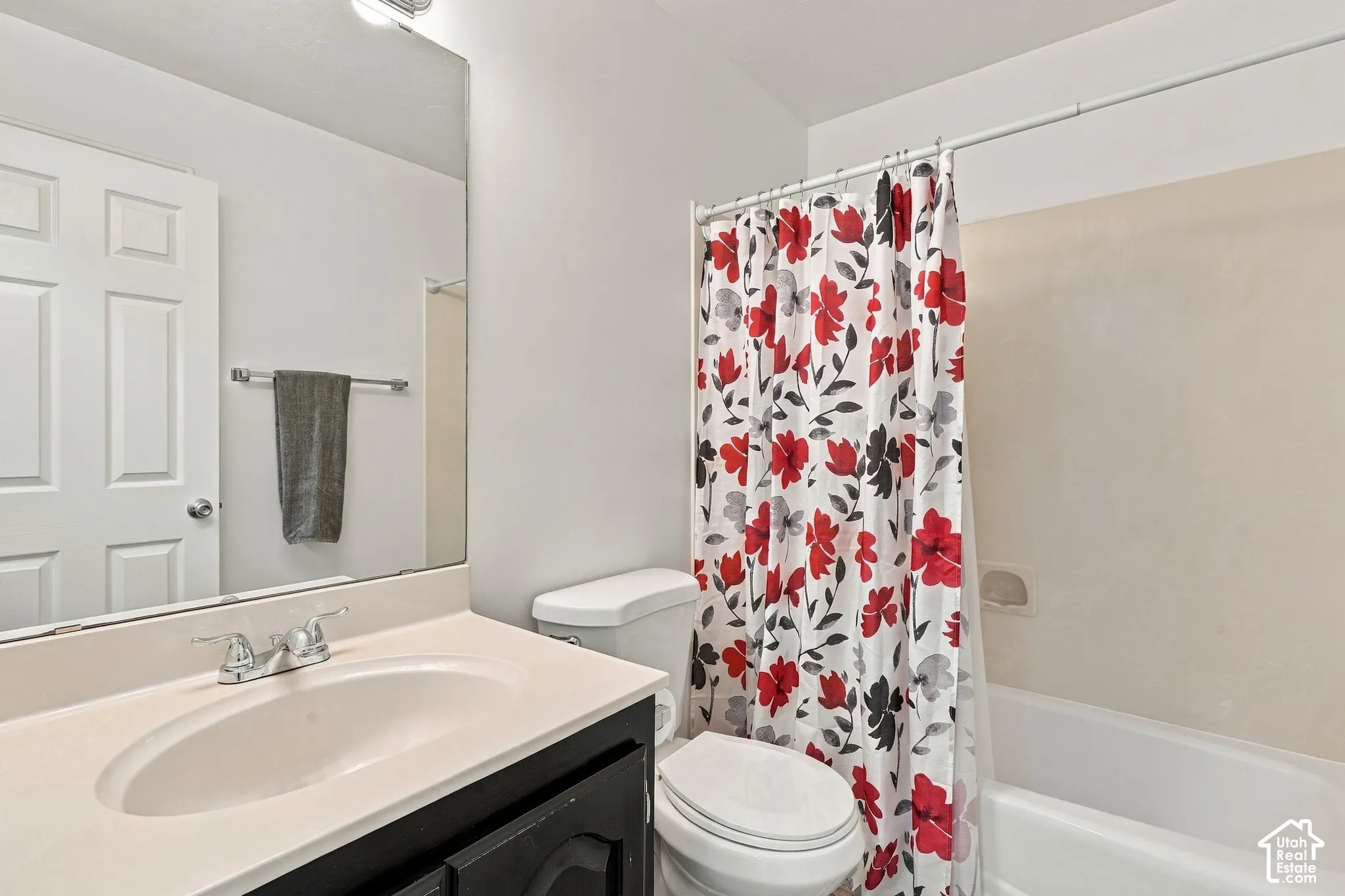 White vanity with integrated sink, chrome faucet, and expansive wall-mounted mirror