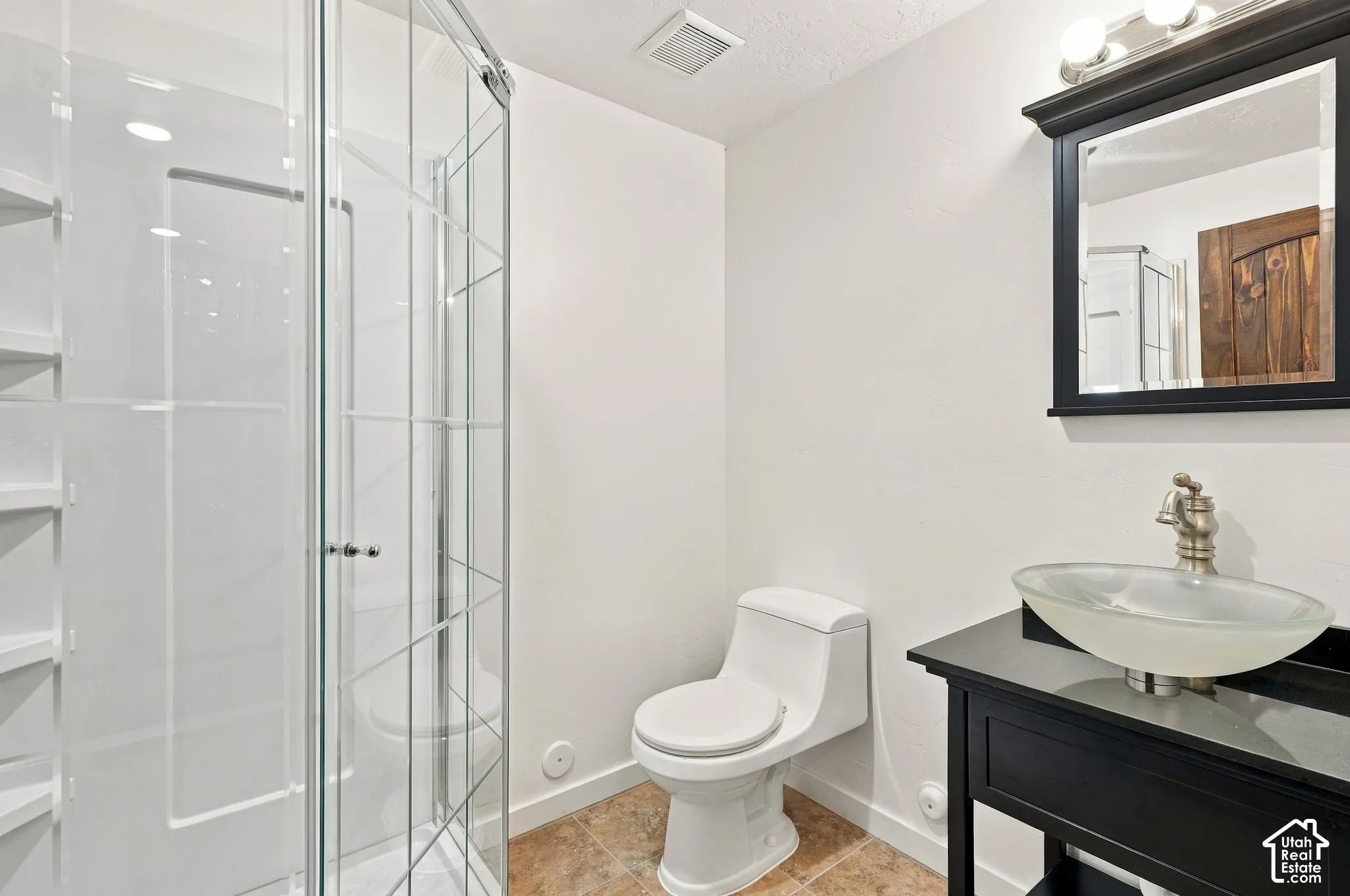 Glass-enclosed shower with white shelving