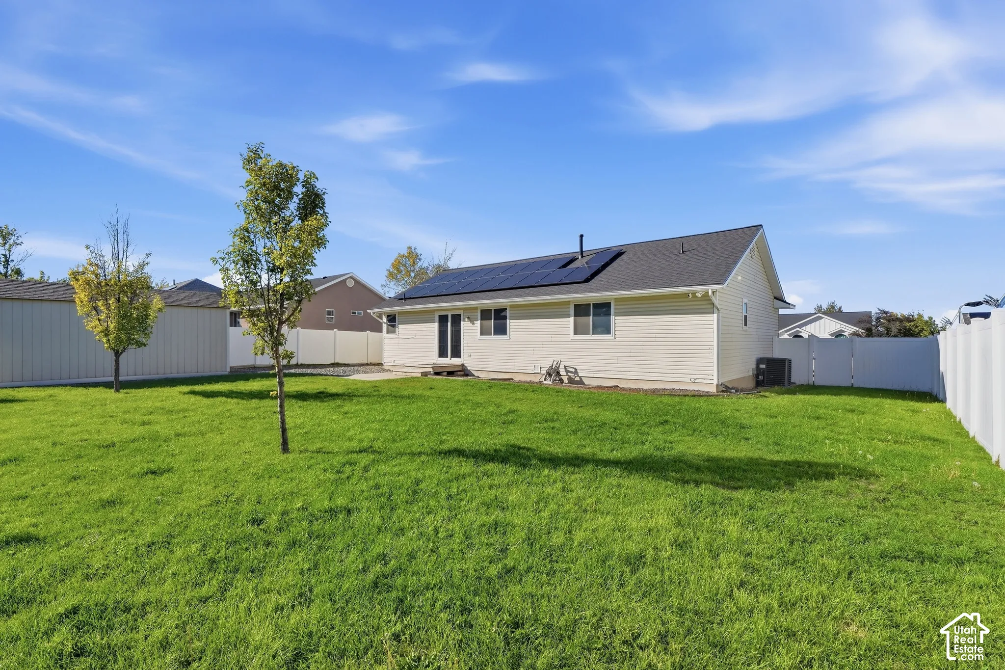 Expansive green lawn with a white privacy fence and a rear patio