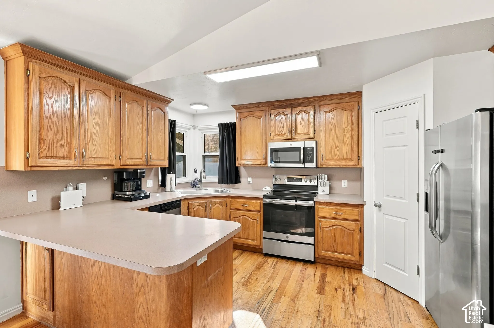 Well-appointed kitchen featuring wood cabinetry, stainless steel appliances, a breakfast bar, and wood-finish flooring