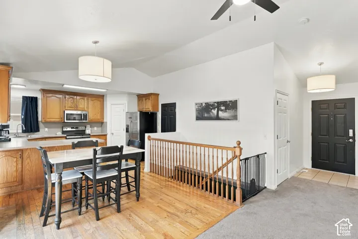 Wood-finish flooring, wood cabinetry, stainless steel appliances, breakfast bar, and wood stair railing