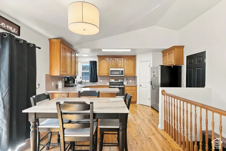 Kitchen featuring wood cabinetry, stainless steel appliances, and a wood-finish flooring