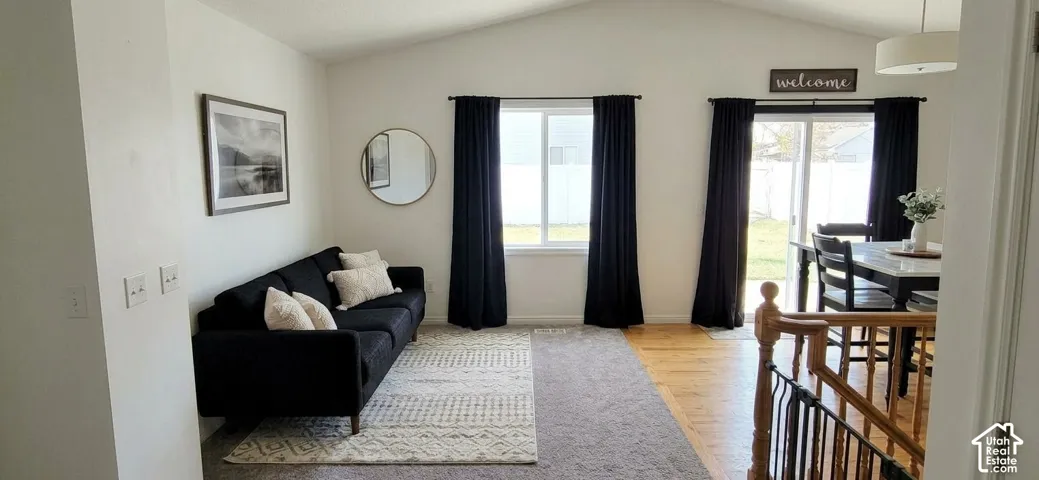 Vaulted ceilings, carpeted and wood-finish flooring, sliding glass door, and recessed lighting
