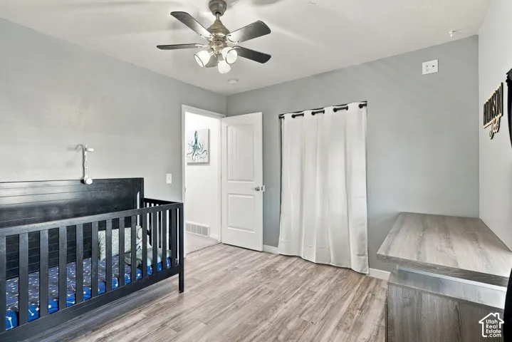 Wood-finish flooring, ceiling fan with integrated lighting, and a solid core interior door