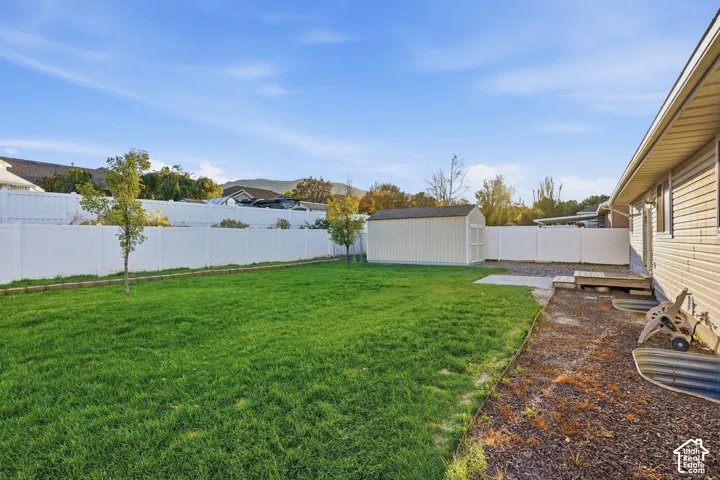 Expansive grassy yard with a white privacy fence and a detached storage shed