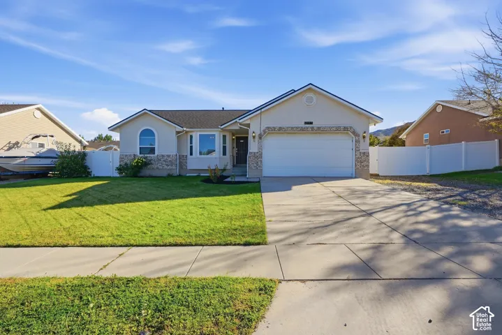 Curb appeal featuring a manicured lawn, a concrete driveway, a two-car garage, and an arched window