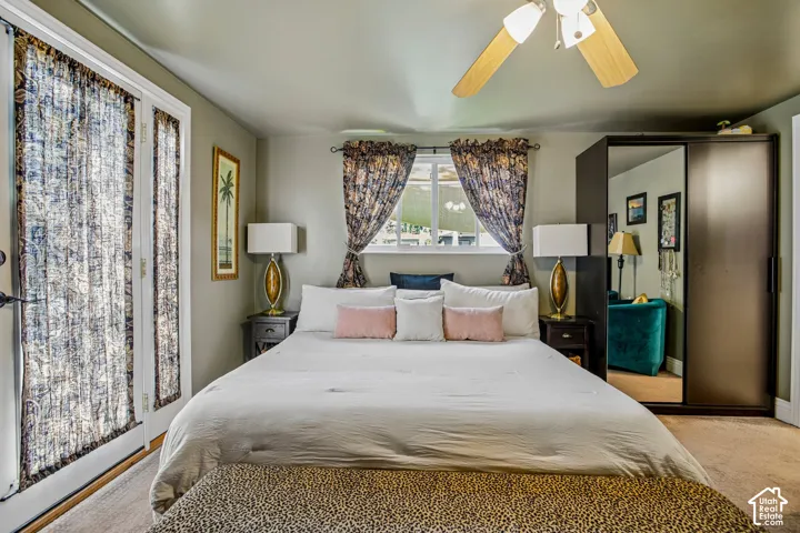 French doors with sheer privacy curtains, a central window with patterned drapes, a ceiling fan with light fixture, and a built-in wardrobe with mirrored doors