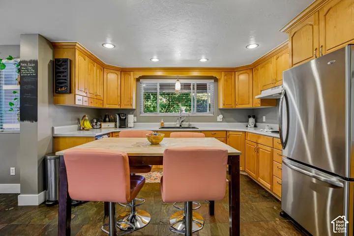Kitchen featuring wood cabinetry, recessed lighting, a stainless steel refrigerator, and a window above the sink