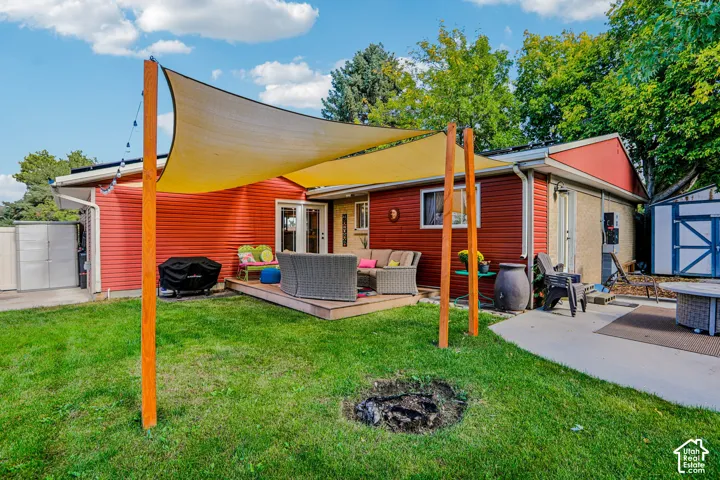 Charming red exterior home with covered patio featuring a retractable shade canopy supported by wooden posts