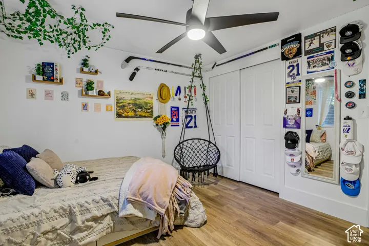 Wood-finish flooring, ceiling fan, white bi-fold closet doors, and wall-mounted shelving