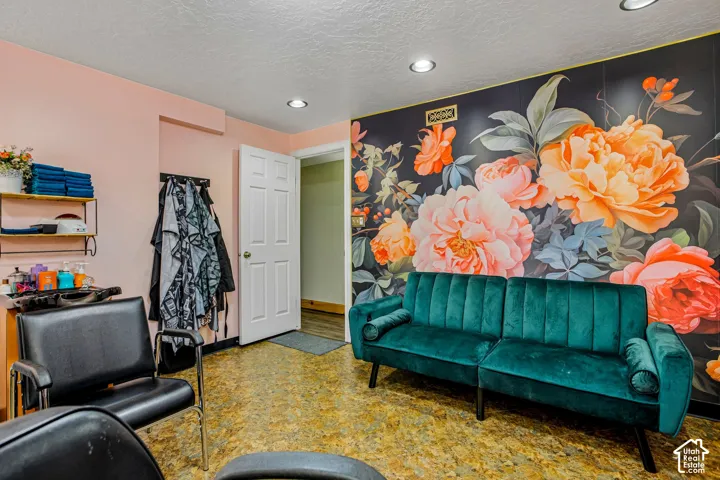 Recessed lighting illuminates a space featuring a vibrant floral accent wall, a light-toned wall, and wood-finish flooring