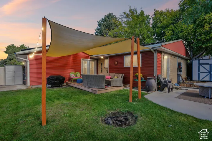 Expansive backyard featuring a large deck, sun shade, and multiple storage sheds