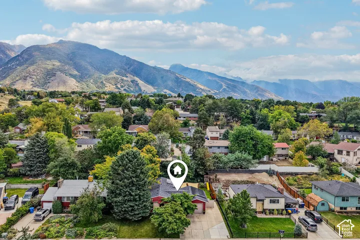 Aerial view showcasing a residential property nestled within a tree-lined neighborhood setting, with mature landscaping framing the home