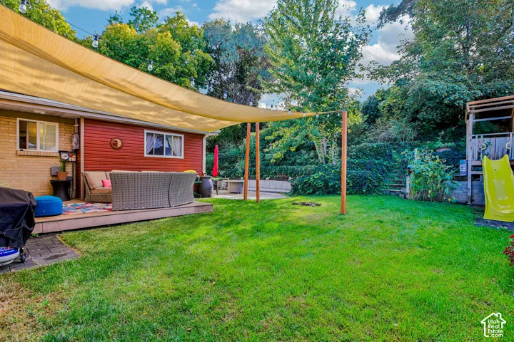 Expansive backyard featuring a manicured lawn, a raised wood deck, and a shade sail