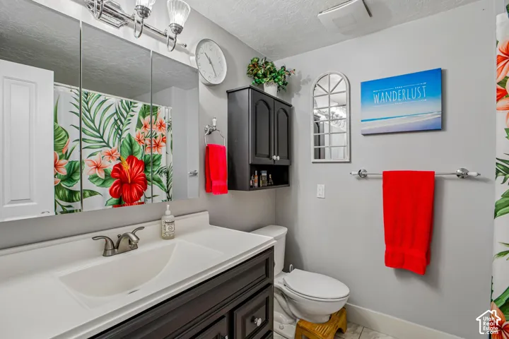 Vanity with an integrated sink and brushed nickel faucet, wall-mounted mirror cabinet, wall-mounted light fixture, and tile flooring