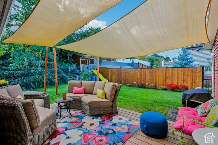 Expansive backyard featuring a wood deck, manicured lawn, and mature landscaping