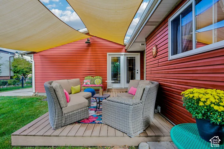 Outdoor deck with wide plank flooring, red siding, and white trim windows