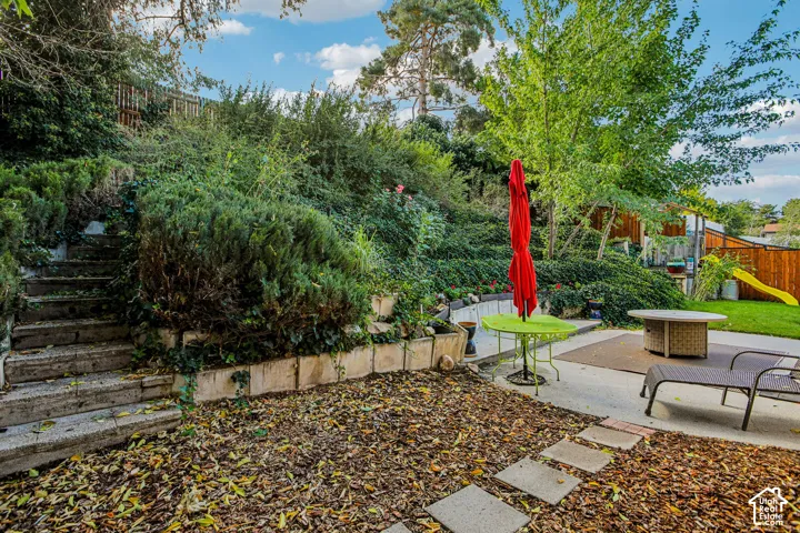 Tiered landscaping with stone steps, concrete patio areas, and a grassy expanse