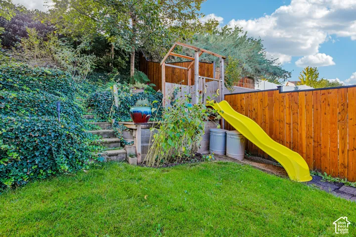 Expansive backyard with a manicured lawn, established landscaping, and a wood privacy fence