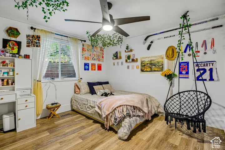 Wood-finish flooring, recessed window with blinds, ceiling fan with integrated lighting, built-in shelving, and white walls