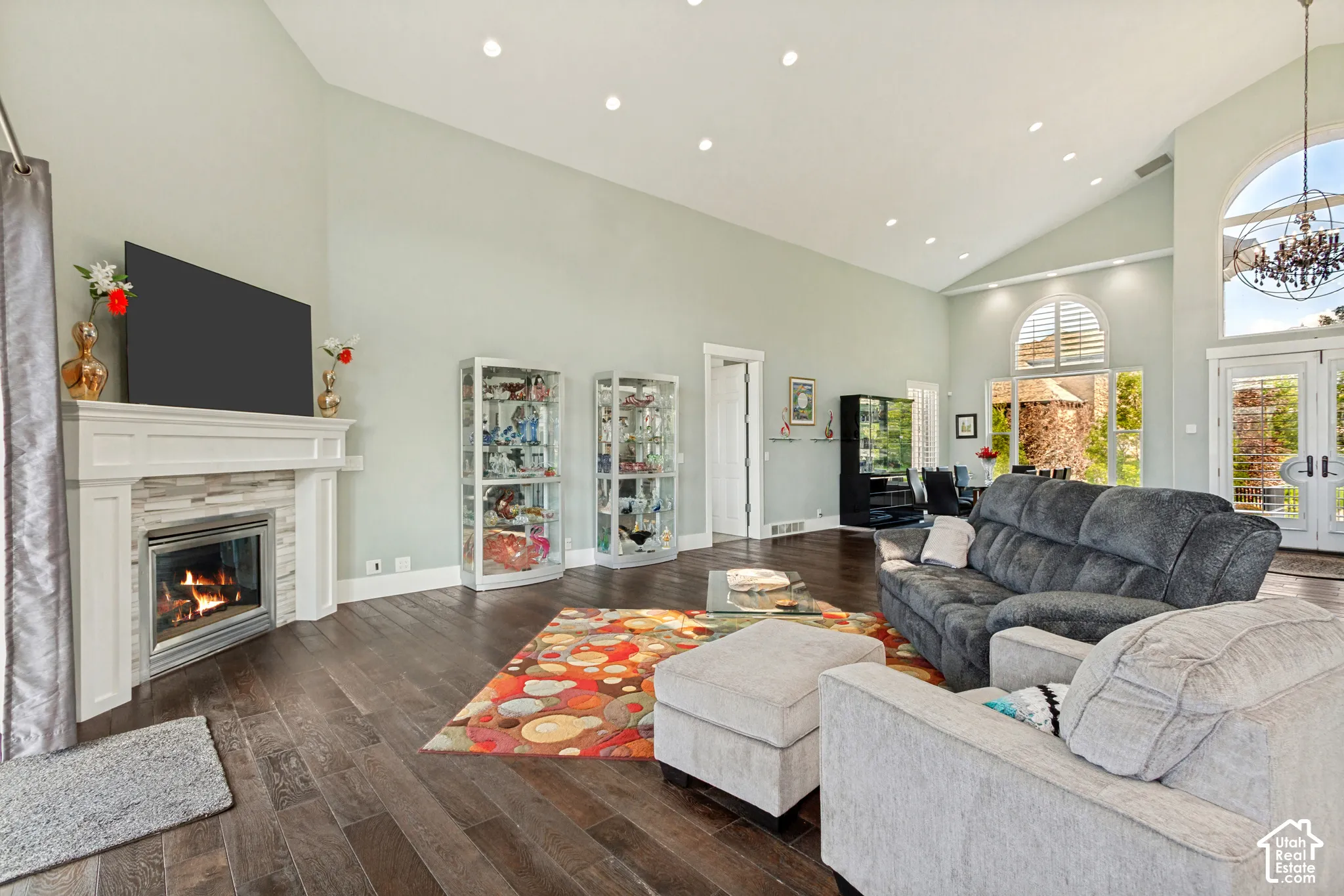 Spacious great room anchored by a gas fireplace with marble surround and built-in cabinetry, complemented by recessed ceiling lighting and dark wood-finish flooring throughout