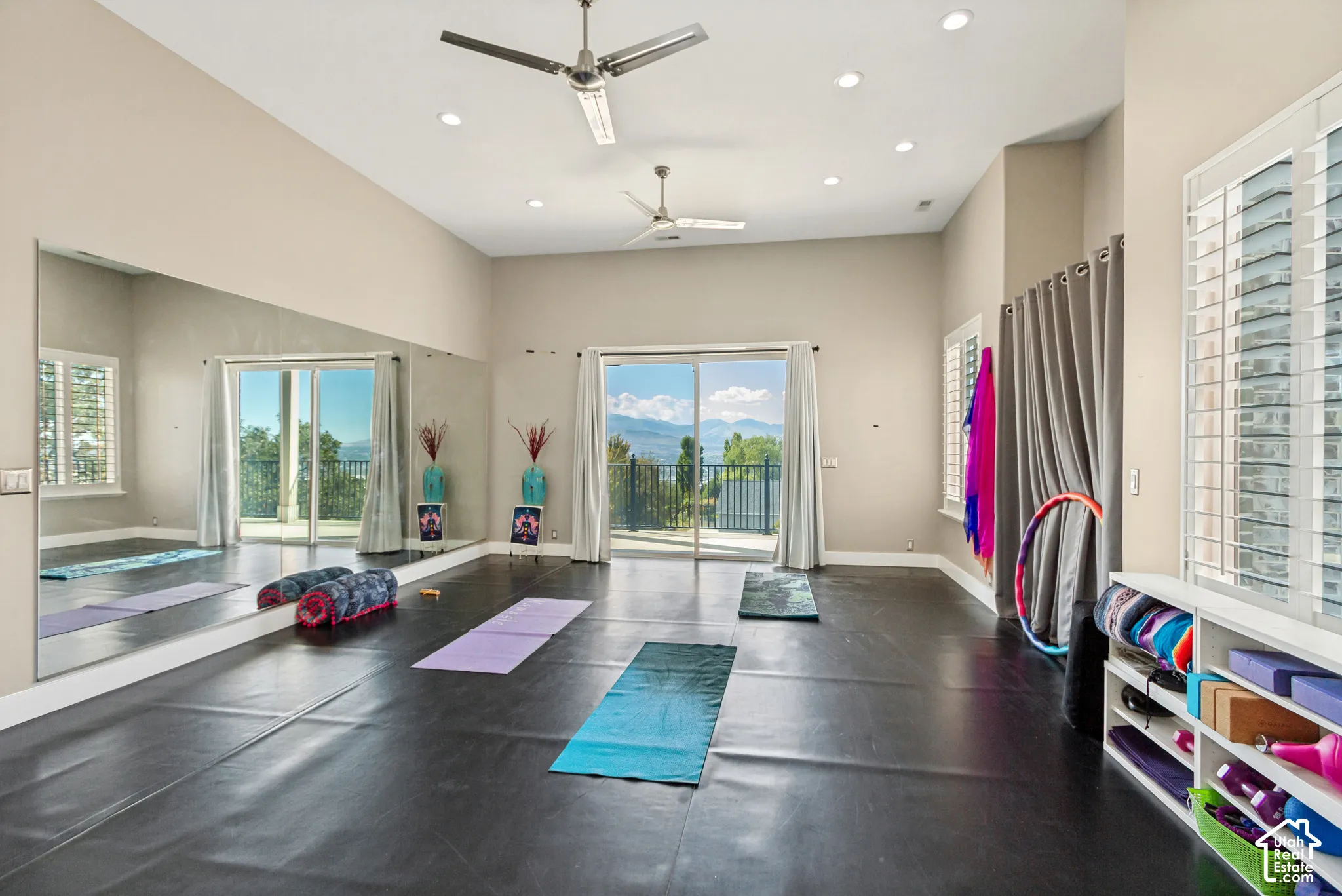 High ceilings with recessed lighting, full-wall mirror, two ceiling fans, and sliding glass doors to outdoor spaces