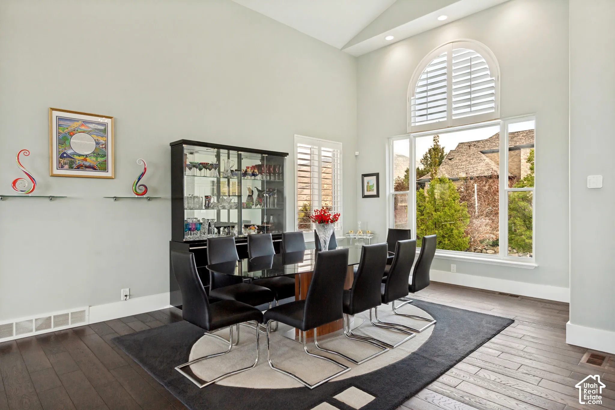 Vaulted ceiling, arched window with plantation shutters, wood-finish flooring, built-in display cabinetry, recessed lighting