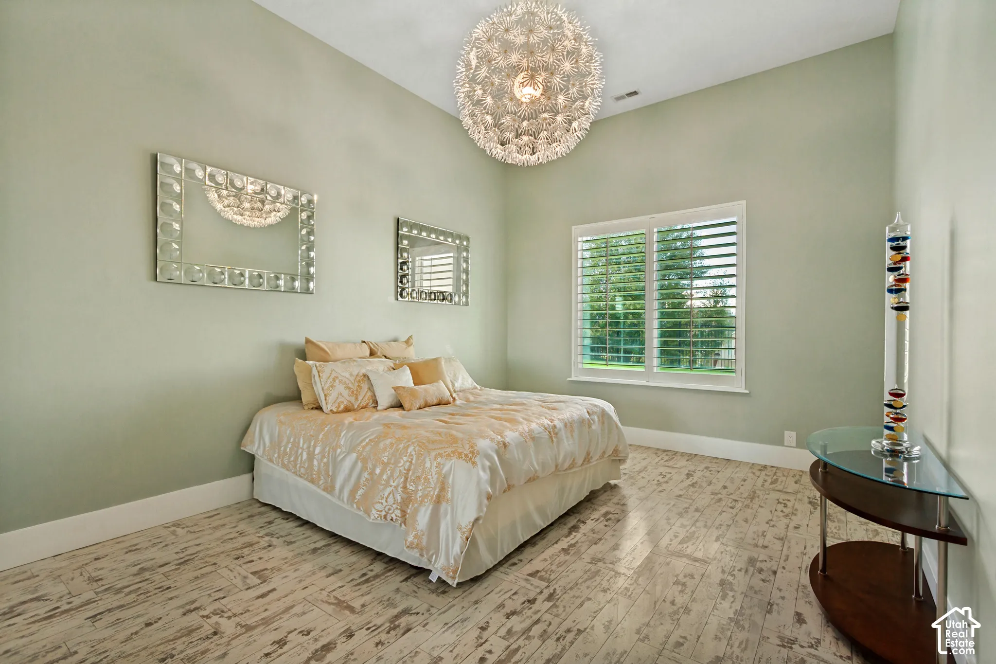Vaulted ceiling with a contemporary chandelier, wood-finish flooring, and window with plantation shutters