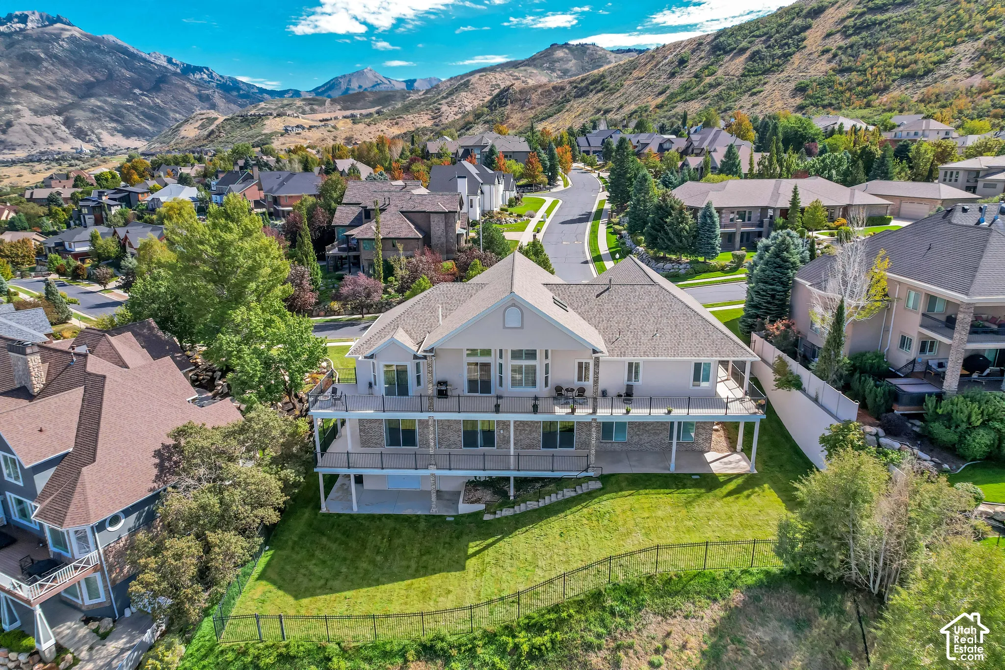 Expansive property featuring a multi-level deck, lower patio, and a sloped, manicured lawn