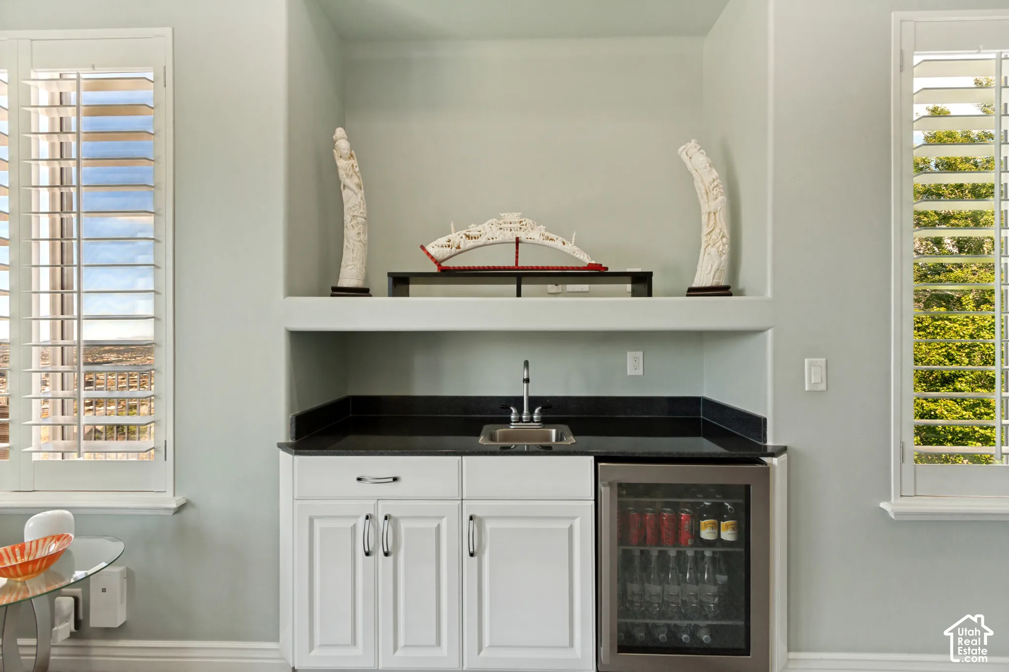 Built-in wet bar with white cabinetry, dark countertop, and stainless steel beverage refrigerator