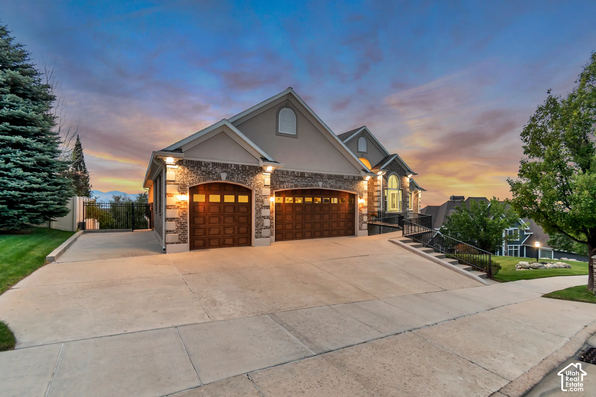 Striking two-car garage with wood-finish doors and stone-accented pillars anchors this elegant driveway