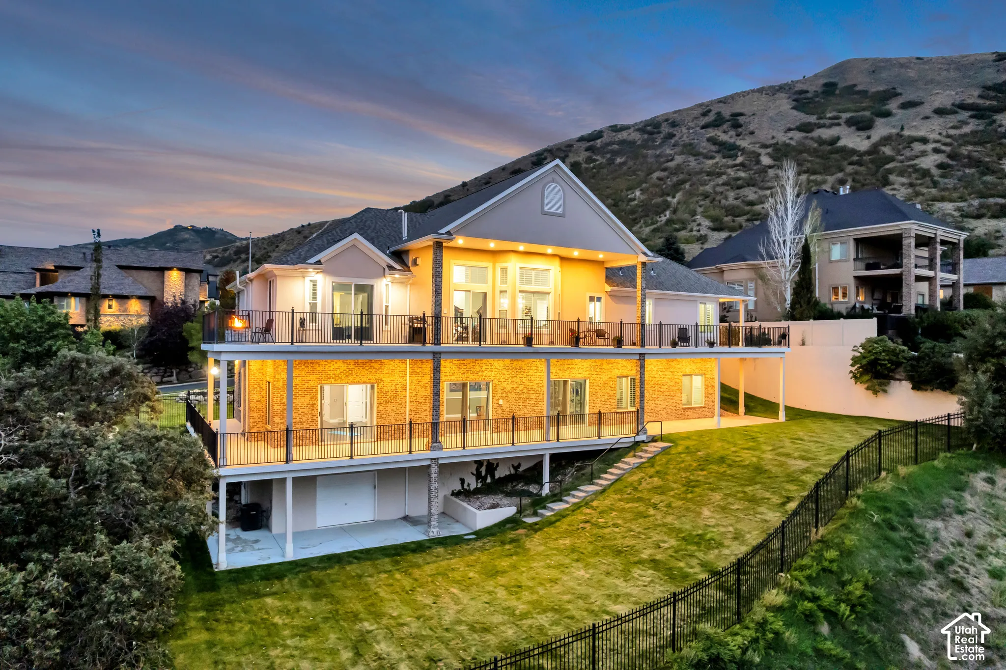 Multi-level property with an expansive lawn, multiple decks featuring dark railings, and a brick-finish lower level