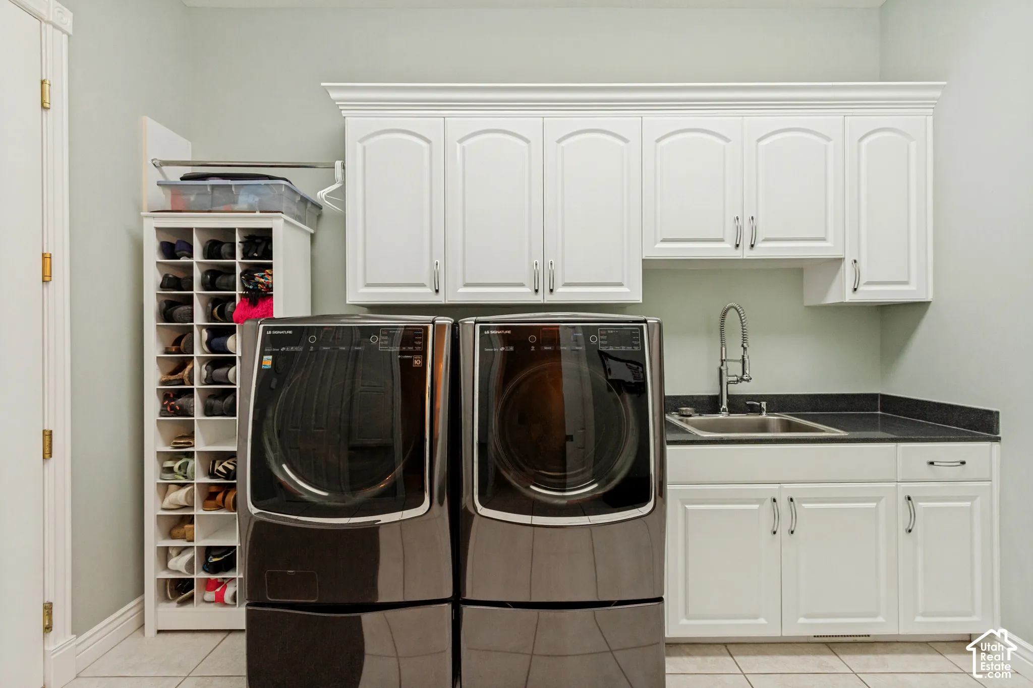 Laundry area featuring white cabinetry, a utility sink, and stone-finish countertops