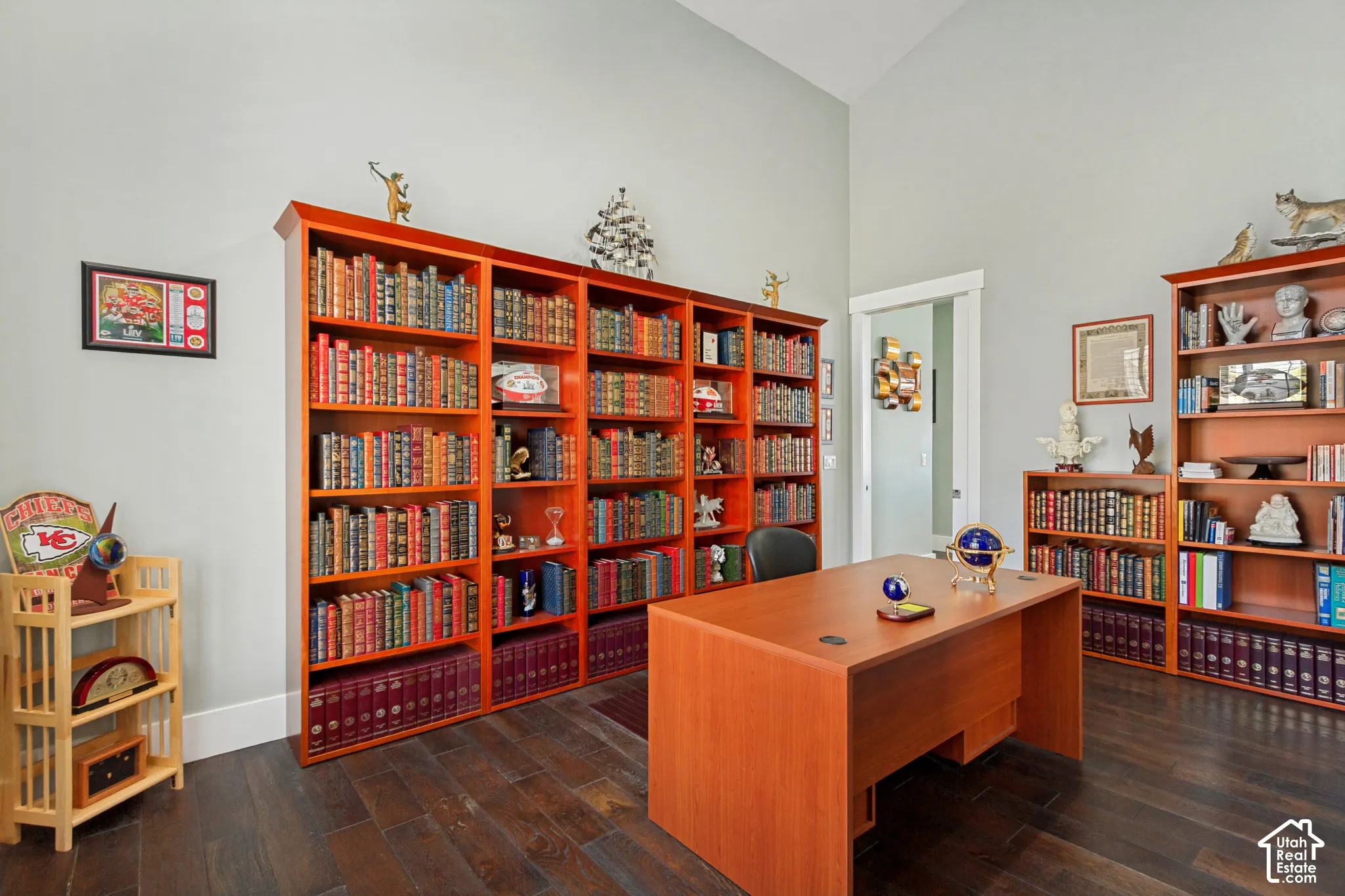 Vaulted ceiling, wood-finish flooring, built-in shelving, and white trim