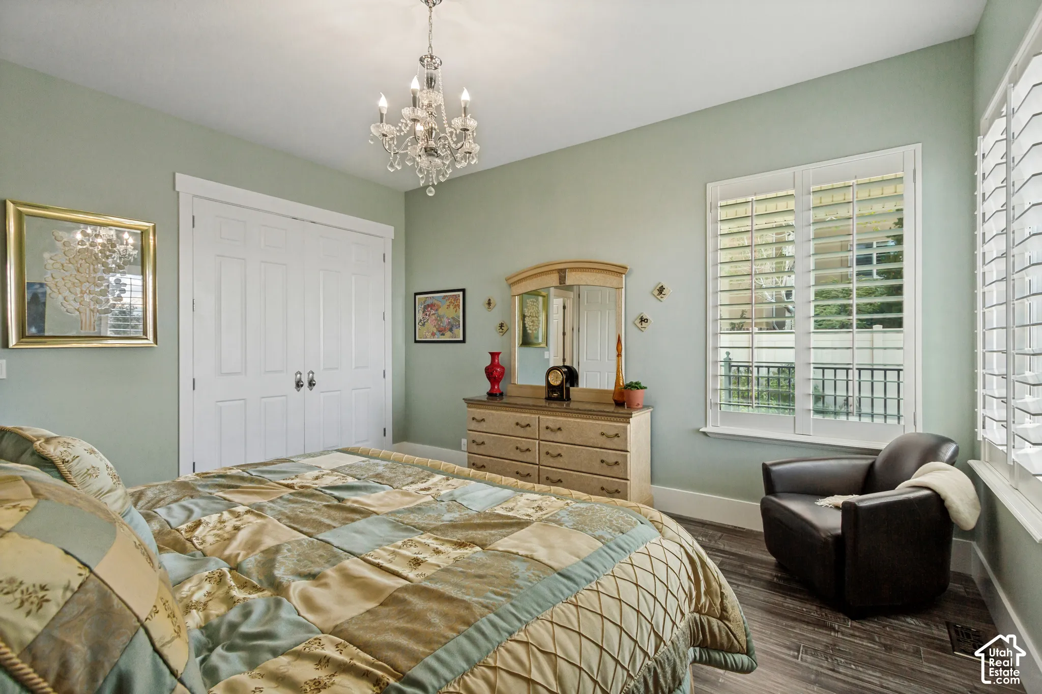 Wood-finish flooring, white window shutters, white bi-fold closet doors, and a crystal chandelier