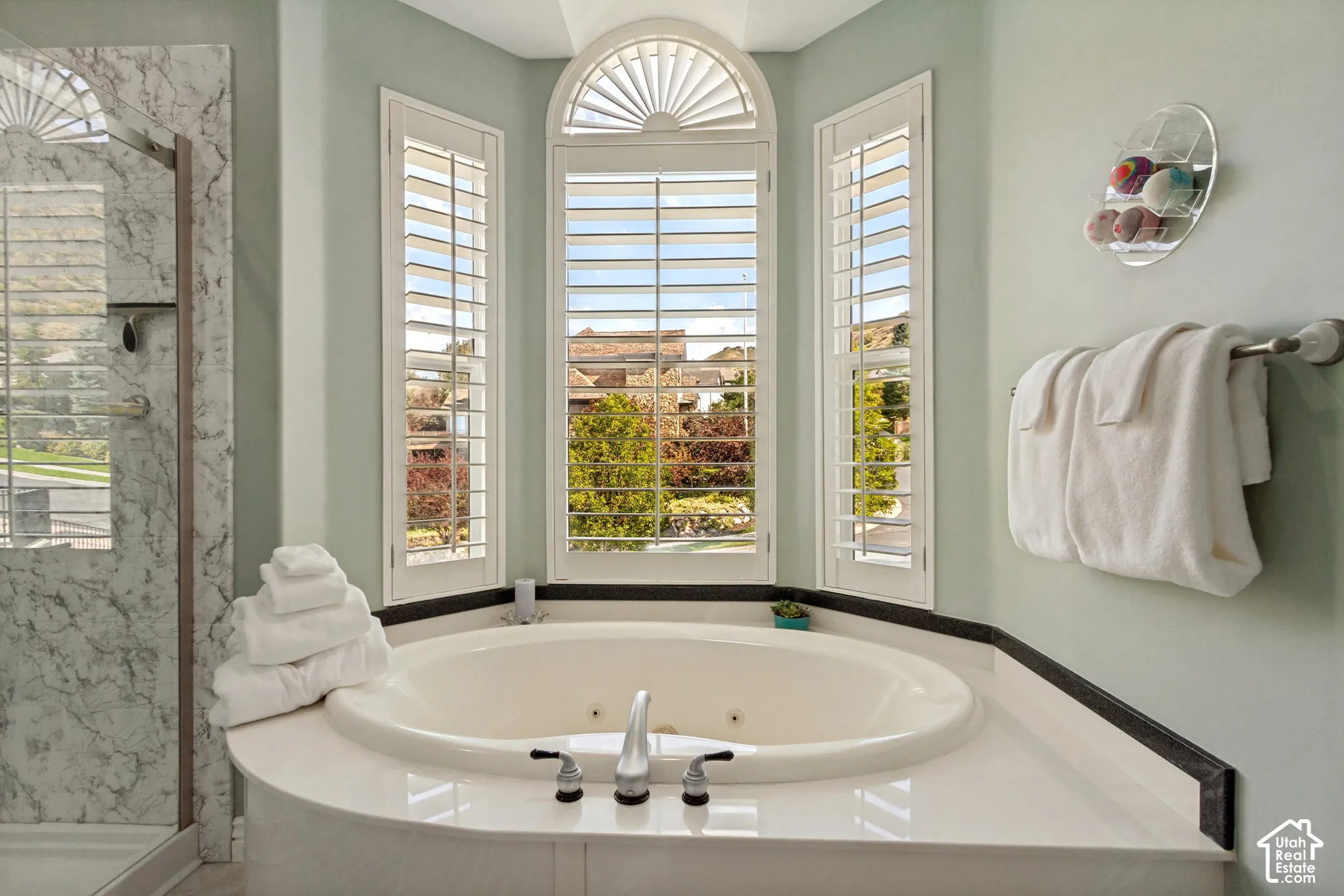 Corner soaking tub with deck-mounted fixtures, surrounded by a white countertop and dark trim