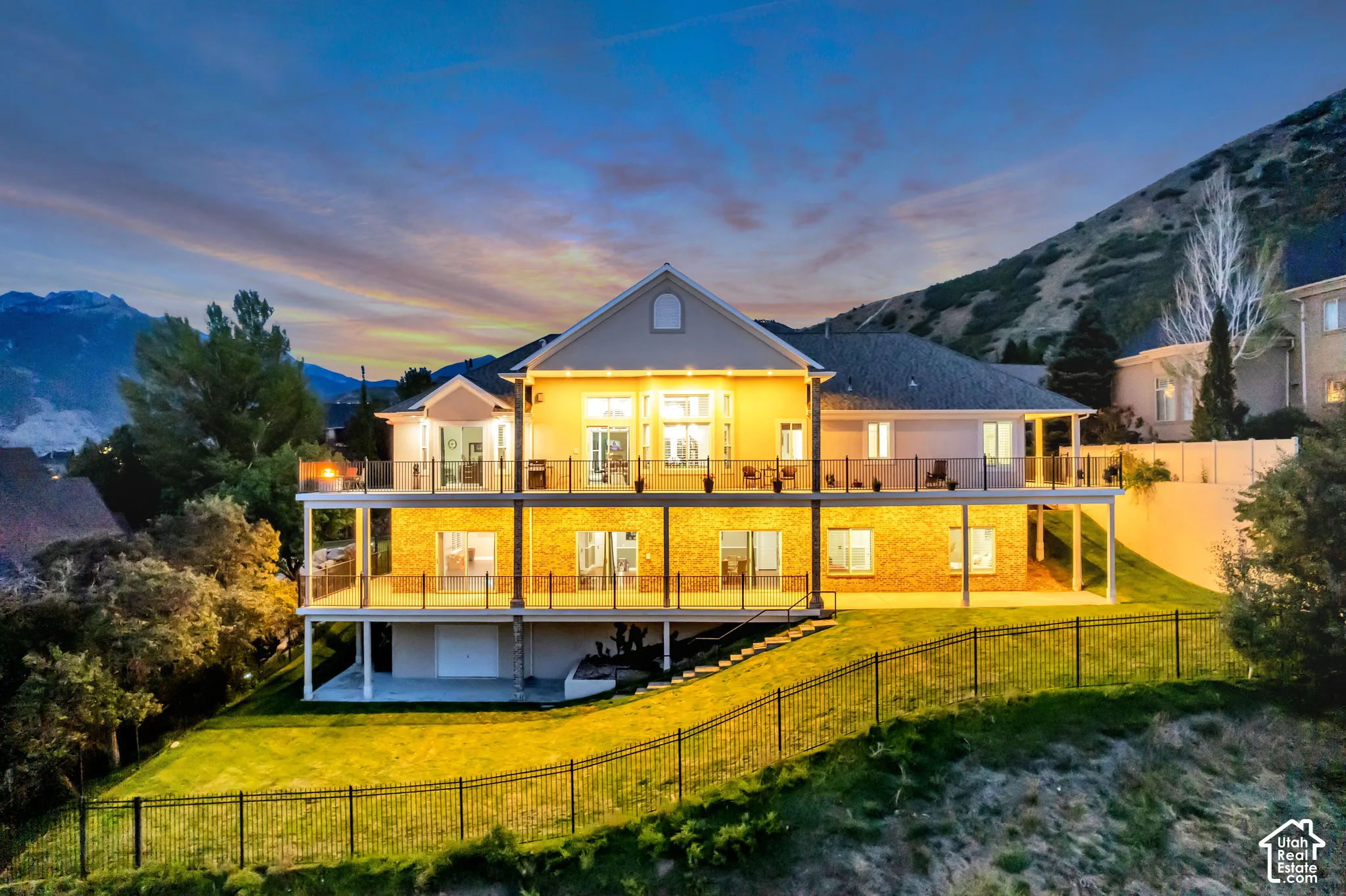 Multi-level property with expansive outdoor decks, glass panel railings, and a fenced, sloped yard