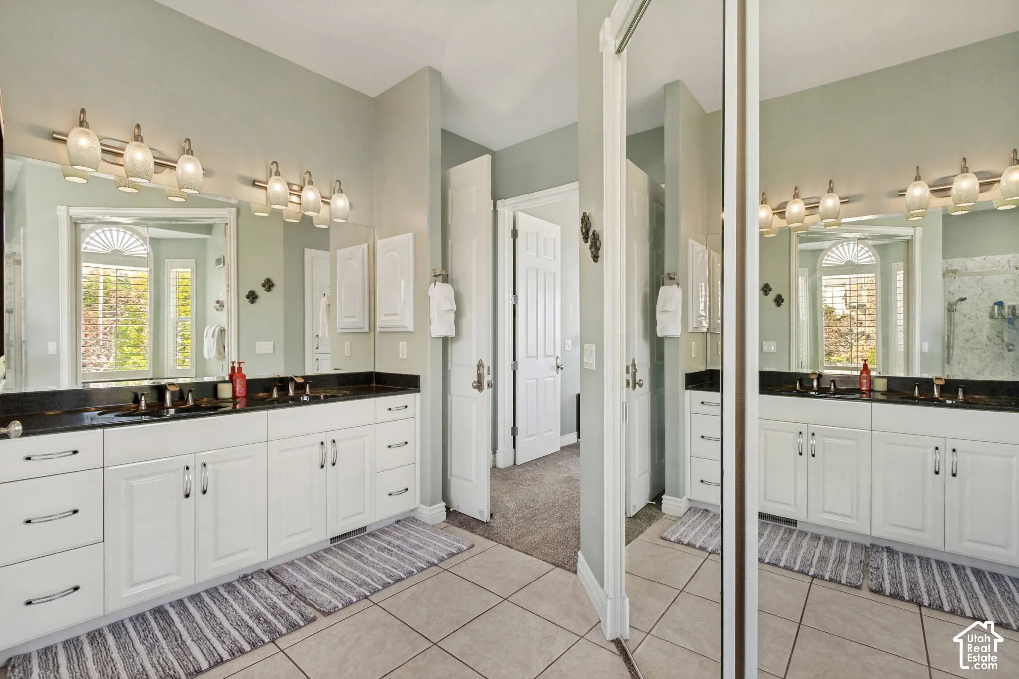 Dual vanity with white cabinetry, dark countertops, and individual sinks