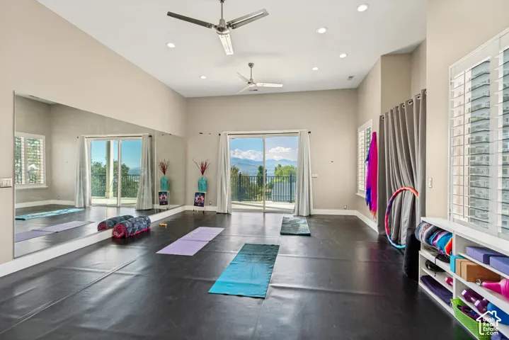 High ceilings with recessed lighting, full-wall mirror, two ceiling fans, and sliding glass doors to outdoor spaces
