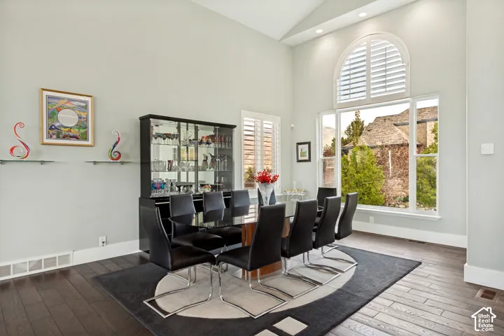 Vaulted ceiling, arched window with plantation shutters, wood-finish flooring, built-in display cabinetry, recessed lighting