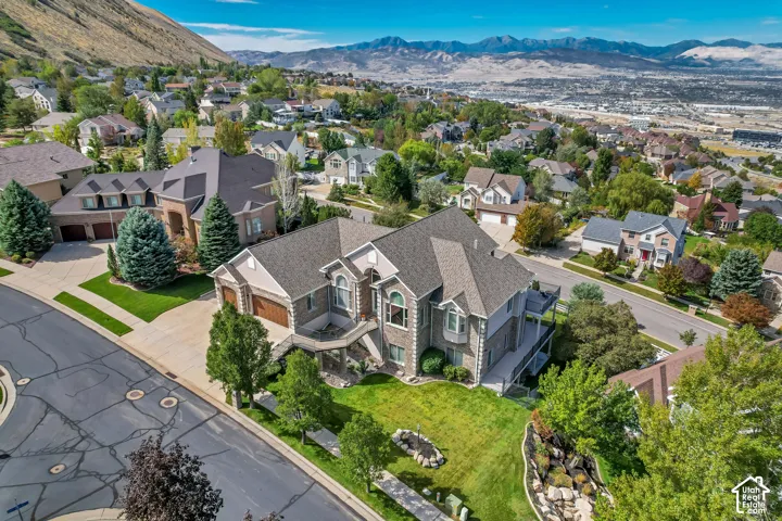 Two-story residential exterior with a stone and siding facade, featuring a prominent bay window, attached two-car garage, and a spacious front lawn with mature landscaping