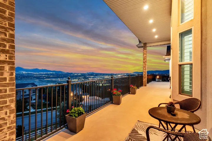 Covered balcony featuring recessed lighting, brick and stone veneer accents, and a metal railing