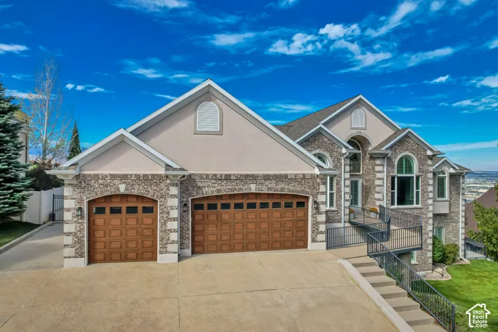 Stunning two-story residence showcasing stone and stucco exterior elevations, dual wood-finish garage doors with panel detailing, and a wide concrete driveway