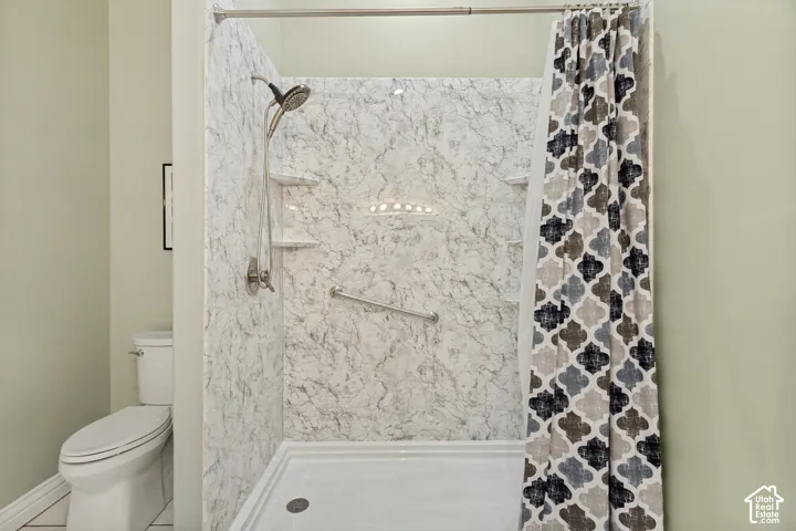 Shower with marble-patterned wall panels, integrated shelving, and a grab bar