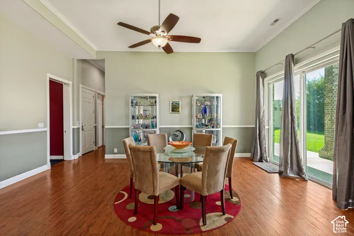 Wood-finish flooring throughout, ceiling fan with integrated lighting, crown molding, and sliding glass doors to outdoor patio