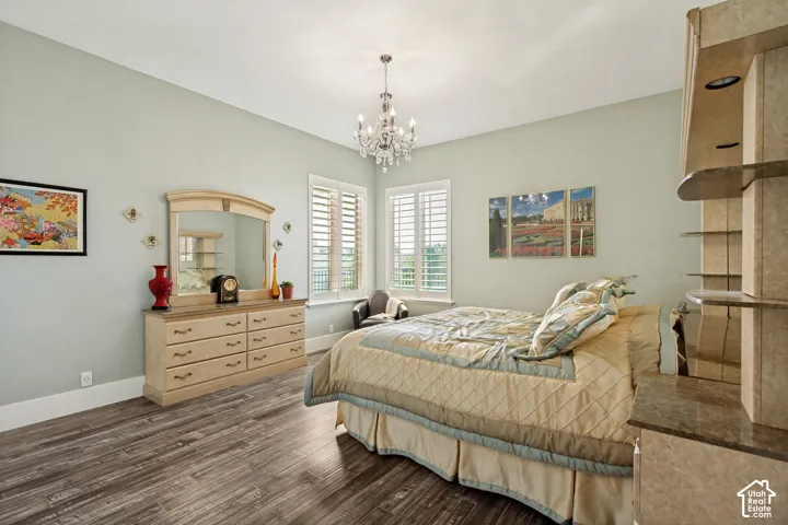 Spacious primary bedroom featuring soft sage-green walls, wood-finish flooring, and abundant natural light from dual shuttered windows