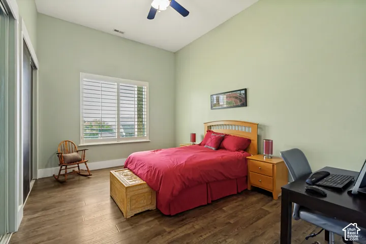 Vaulted ceiling with a ceiling fan, wood-finish flooring, and a window with white louvered shutters