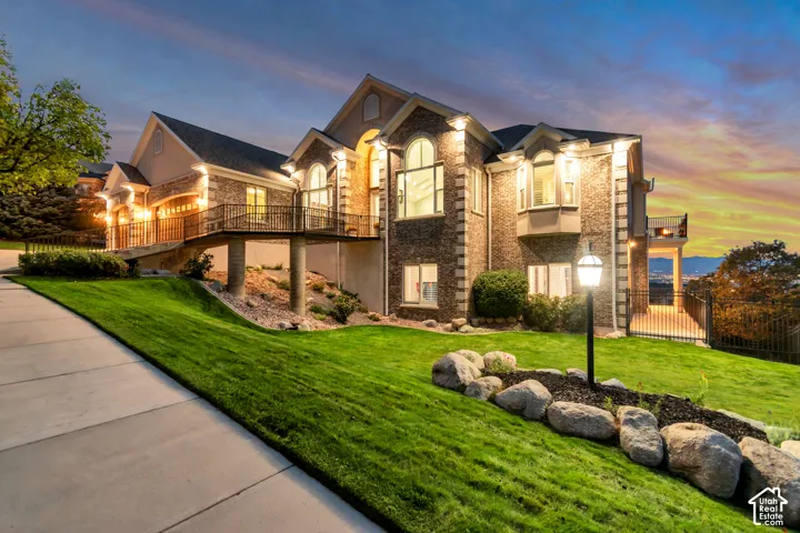 Brick and stucco exterior with arched windows, an elevated balcony, and an integrated garage