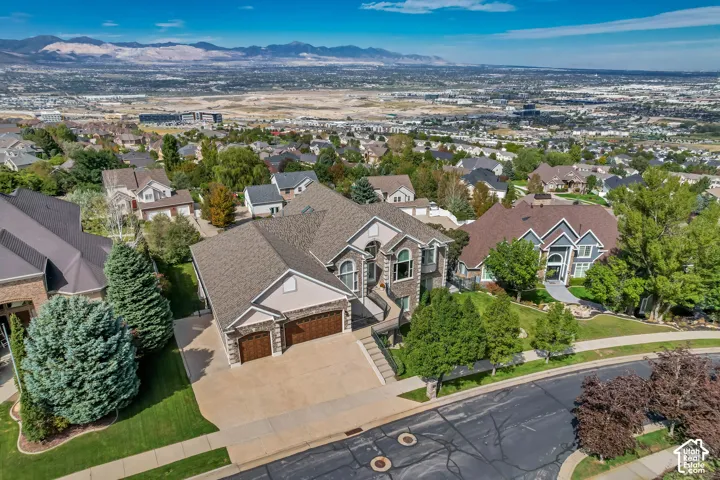Expansive concrete driveway with a two-car garage, stone facade accents, and a pitched shingle roof