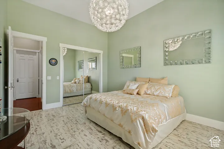 Vaulted ceiling with an ornate chandelier, mirrored closet doors, and wood-finish flooring